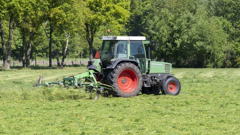 Traktor ute på grønn eng