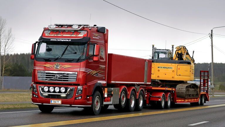 Rød lastebil med gravemaskin bak